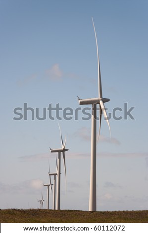 Wind turbines on a wind farm in Scotland, Europe. The sun is setting on a summer evening.