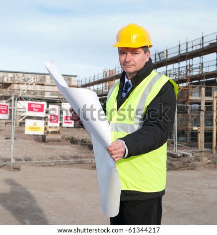 Architect or engineer at work on a building site. Checking plans against the construction work. Looking confidently at camera.