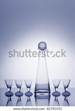 Modern, slim decanter and five glasses toned blue and backlit with a halo and plenty of copy space.