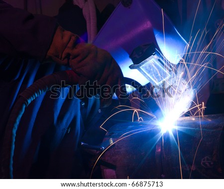 Welder uses torch to make sparks during manufacture of metal equipment.