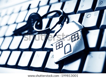 Mortgage concept with keys and house-shaped key ring on laptop keyboard