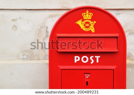Red postal box against grunge wall in Copenhagen, Denmark