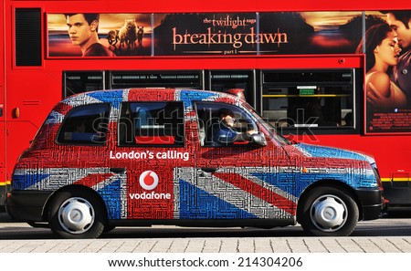 LONDON, UK - NOVEMBER 18, 2011: Old taxi tuned with Union Jack flag against traditional double-decked red bus on London streets