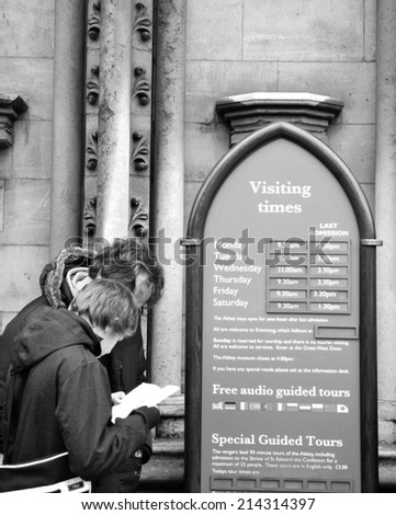 LONDON, UK - NOVEMBER 19, 2011: Tourists check visiting hours at Westminster Abbey, major tourist landmark in London
