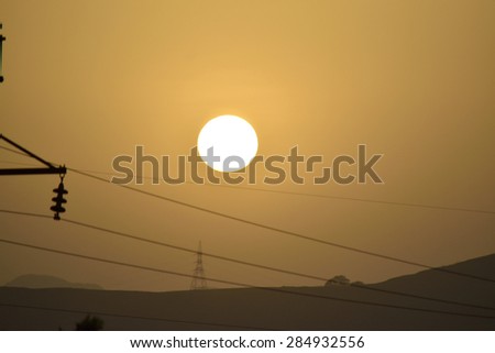 Round sun at dusk in the middle of a valley