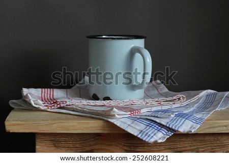 the enameled blue mug and towel on a wooden table