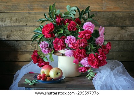 Bouquet from red and pink roses, strawberry and apples on a wooden table. A still life with roses and strawberry.