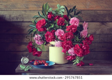 Red and pink roses against a wall from boards. A still life with hours and roses. A still life with a bouquet.