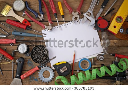 Tools on a timber floor, the top view. Tools are spread out round a notebook for records. A place for your text.