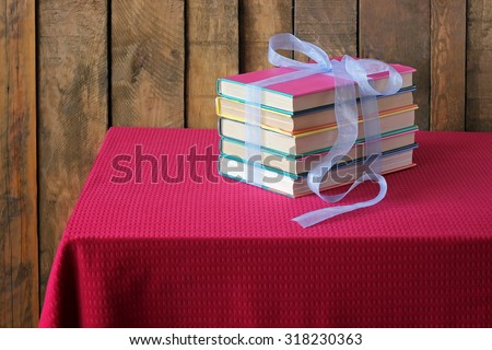 The books which are tied up by a blue tape lie on a table with a red cloth.  A still life with books.