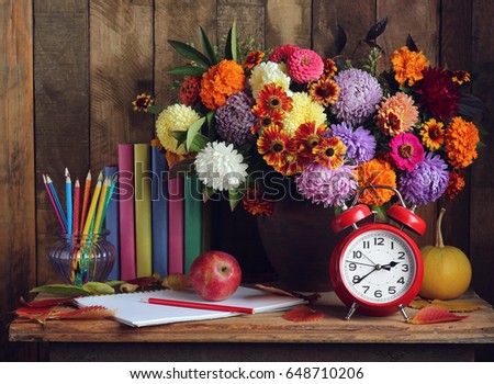 Back to school. Alarm clock, bouquet, apples, and books on the table.  The teacher\'s day. The day of knowledge. September 1.