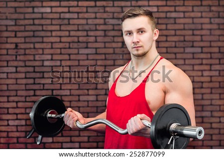 Young athlete doing barbell bench press standing on brick wall background.