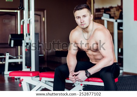 Young athlete sitting on a bench in the gym after a workout .