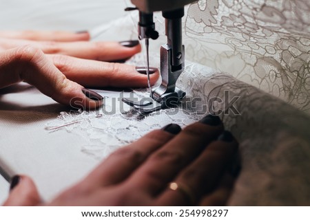 Seamstress , sewing lace wedding dress on the sewing machine .