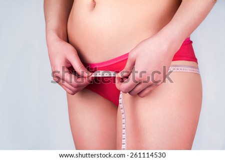 The girl in red underwear measuring hips meter tape.close-up