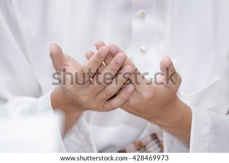 Muslim person wearing traditional malay clothes and praying in the mosque, Man raising hand pray