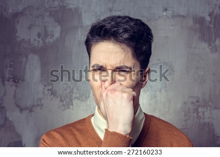 Young man holding his nose against a bad smell