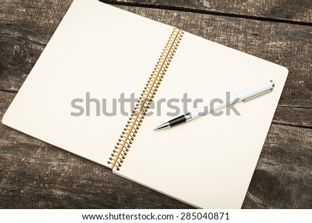 notebook and pen on wooden desk