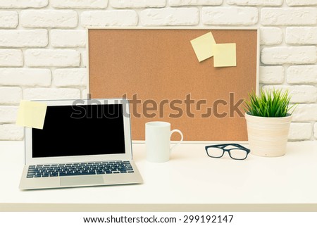 Working desk, laptop, cork board. Office interior