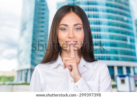 Attractive business woman with finger on lips, gesturing for quiet