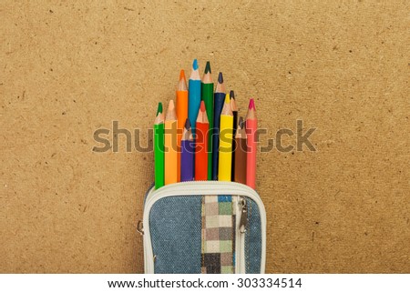 Pencil-case with colorful pencils on cork background