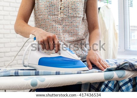 Closeup of woman ironing clothes on ironing board