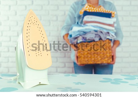 Housewife bringing a huge pile of laundry on the ironing board