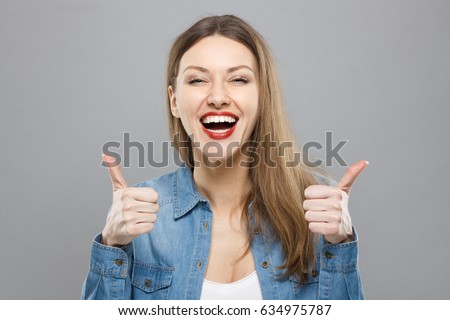 Closeup of young optimistic female isolated on grey background showing thumps up with positive emotions of content and happiness. Copyspace, concept of satisfaction with quality and recommendation.