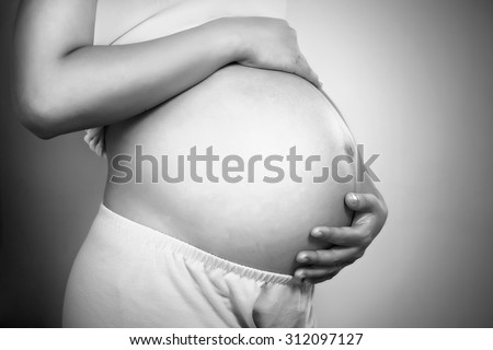 Pregnant Woman Belly. Pregnancy Concept. Isolated on Black Background. Black and white pregnant tummy close up