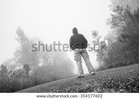 A man stand alone on the rain forest road black and white.
