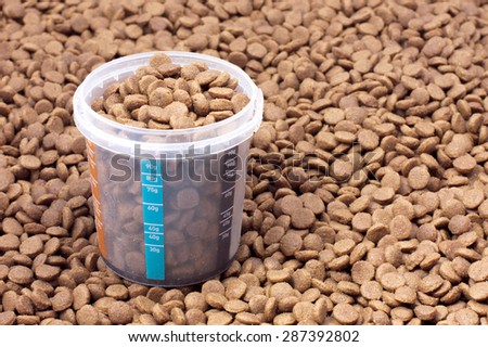 Dry brown pet food (dog or cat) with measure glass