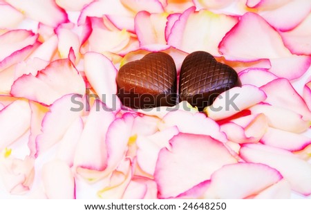 Tender Love - two chocolate hearts over rose petals.