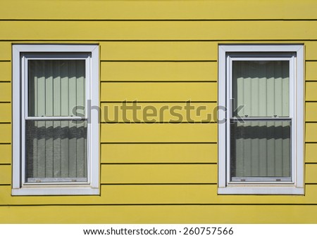 Two windows on a very colorful sided house.