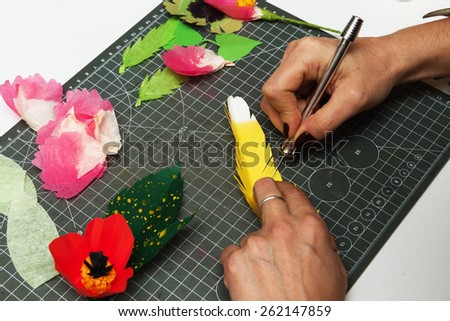 women's hand cutting flower from paper