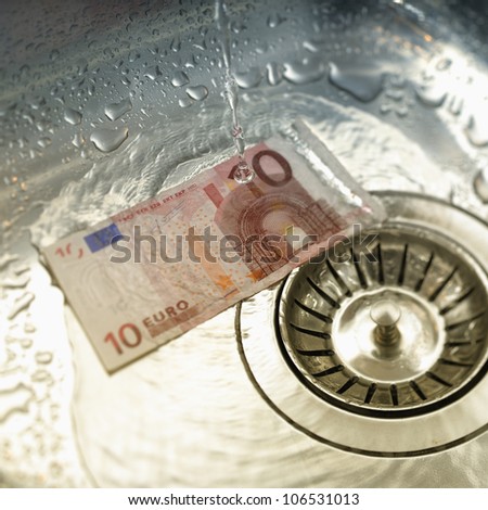 Water rinsing euro note in sink. Tilt shift lens used to accent the note.