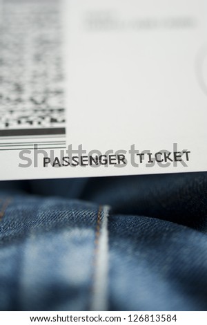 Airline ticket on knees of a passenger. Tilt shift lens used to accent passenger ticket text and jeans