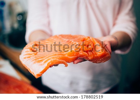 Woman holding fresh piece of fresh raw salmon. Tilt-shift lens used to outline the food \