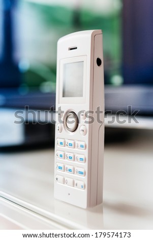 Cordless phone on office table - white color and large display. Tilt-shift lens used to accent the center of the phone and to emphasize the attention its central buttons