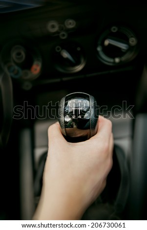 Manual car shift gear changed by hand in automobile interior
