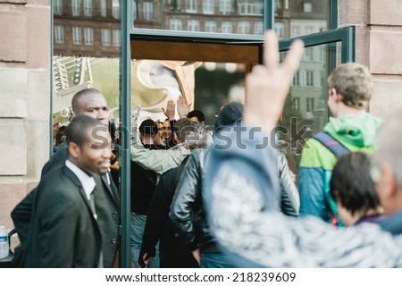 STRASBOURG, FRANCE - SEPTEMBER 19, 2014: First customers entering Apple Store for the new iPhone 6 launch while employees give high-fives as they enter the Apple Inc.