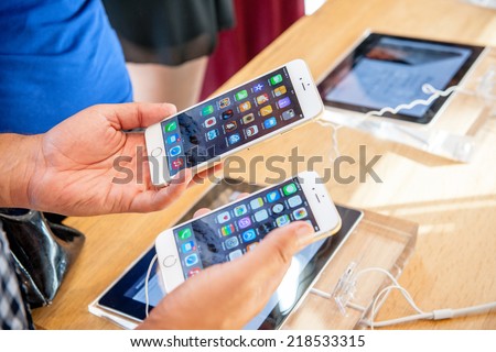 PARIS, FRANCE - SEPTEMBER 20, 2014: Man comparing the new Apple iPhone 6 and iPhone 6 Plus during the sales launch of the latest Apple Inc. smartphones at the Apple store in Paris, France