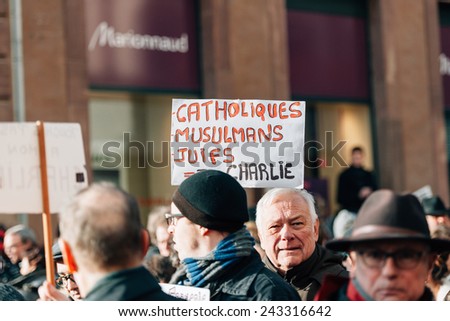STRASBOURG, FRANCE - 11 JAN, 2015:  People hold placards reading \'Catholics, muslims, jews all are Charlie\' during a unity rally (Marche Republicaine) where some 50000 people took part