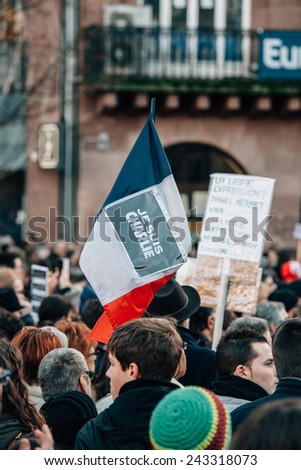 STRASBOURG, FRANCE - 11 JAN, 2015:  People hold placards reading \'Je suis Charlie\' on a French flag during a unity rally (Marche Republicaine) where some 50000 people took part