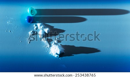 Capsule pill content ingredient scattered on blue medical background with lateral light and long shadows