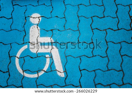 International handicapped symbol painted in white on blue pavement parking space