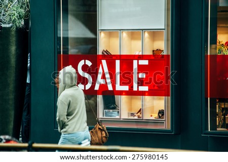 VIENNA, AUSTRIA - JULY 05, 2011: Woman passing in front of large window of luxury store with red on white letters SALE. Vienna is a magnetic attraction for tourists from across the world