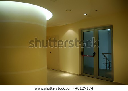 Empty corridor as seen in a modern office building - warm yellow tones and halogen lights