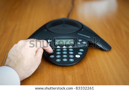 Teleconference - business people hand dialing a number on a modern conference phone. Useful file for your annual report, business brochure and other corporate needs.