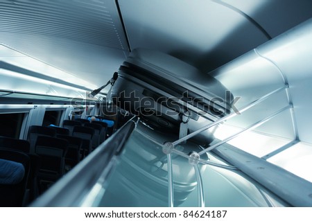 Suitcase on luggage rack in a fast modern train - blue cast business picture