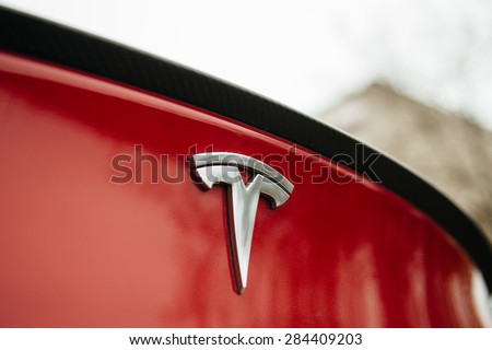 PARIS, FRANCE - NOVEMBER 29: Tesla Motors logo on a red car. Tesla is an American company that designs, manufactures, and sells electric cars